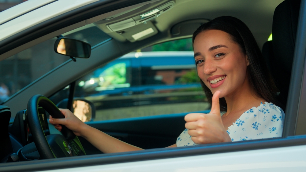Giovane conducente sorridente alla guida della propria auto